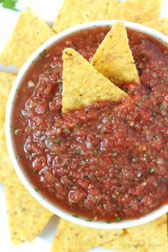 two tortilla chips in a white bowl filled with salsa