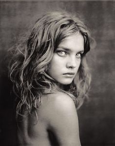 a black and white photo of a young woman with long, wavy hair looking at the camera