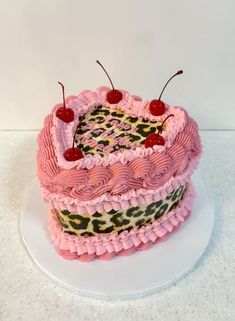 a cake with pink frosting and two cherries on top