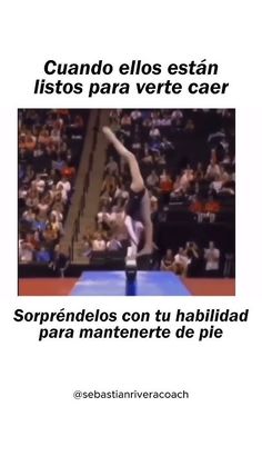 a man doing a handstand on top of a blue mat in front of a crowd