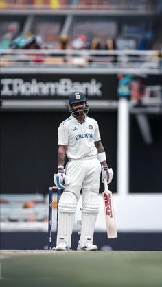 a man standing on top of a field holding a cricket bat and wearing a helmet