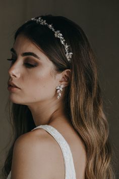 a woman wearing a bridal headpiece with flowers on the side and pearls in the middle