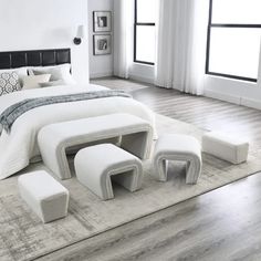 a white bed sitting on top of a wooden floor next to two tables and chairs