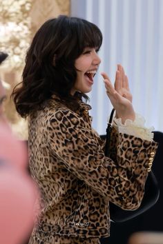 a woman in a leopard print coat clapping