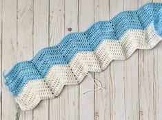 a crocheted blue and white blanket laying on top of a wooden floor