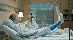 two women in hospital gowns sitting on a bed with an oxygen tube attached to them