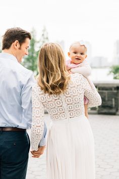 a man and woman holding a baby in their arms while standing next to each other