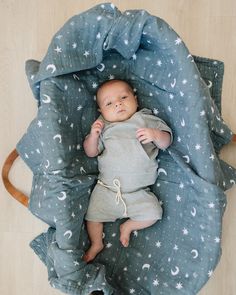 a baby laying on top of a blue blanket covered in stars and crescents next to a wooden rocking chair