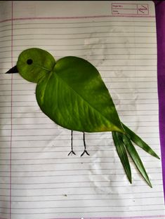 a bird made out of leaves on top of a piece of lined paper with lines in the background