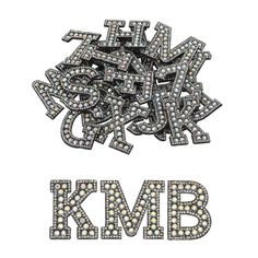 the letters k m b are made up of small white and gray stones, which appear to be surrounded by smaller diamonds