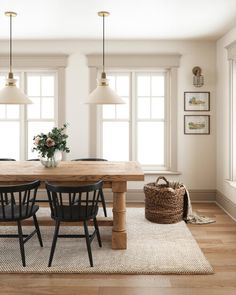 a dining room table with four chairs and a basket on the floor next to it