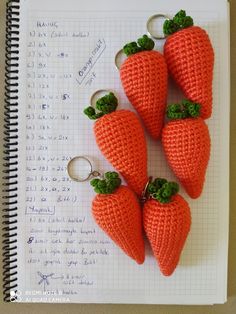 four crocheted carrots sitting on top of a notebook