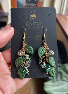 a pair of green leaf earrings with crystal beads