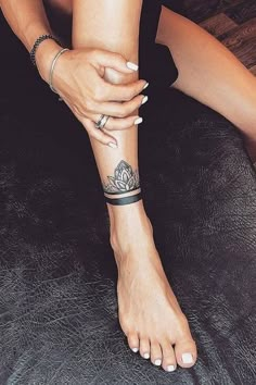 a woman is sitting on the floor with her foot up and tattoos on her arm