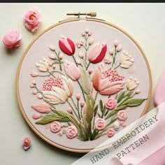 an embroidery pattern with pink flowers and green leaves