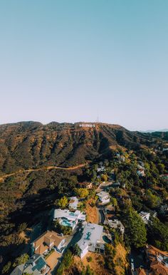 an aerial view of houses and hills in the distance with a blue sky above them