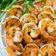 grilled shrimp skewers on a white plate with lemon wedges