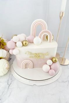 a white cake with pink and gold decorations on it's side, sitting on a marble table