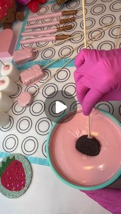 a person in pink gloves is decorating a cake with chocolate and marshmallows