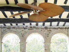 a ceiling fan hanging from the side of a room with arches and arched doorways