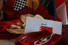 a table topped with red plates and napkins covered in food next to colorful flags