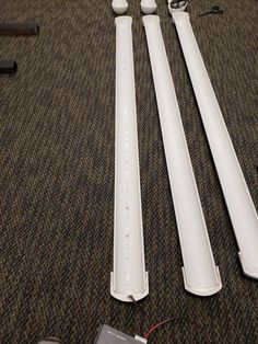 three white plastic tubes sitting on top of a floor next to a remote control unit