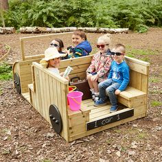 three children are sitting in a wooden train