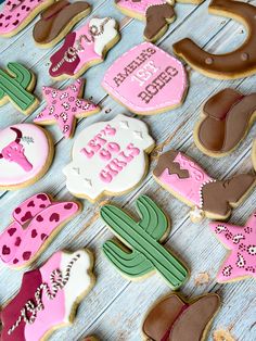 some decorated cookies are laying on a wooden table with pink and green decorations around them