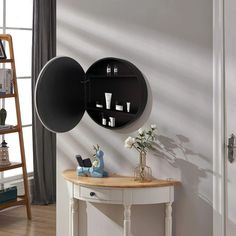 there is a round mirror on the wall next to a table with flowers and candles