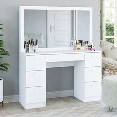 a white dressing table with mirror and stool next to a potted houseplant