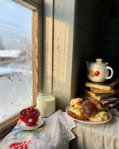 a plate of food on a table next to a window with a cup and saucer