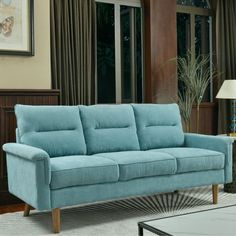 a blue couch in a living room next to a table with a lamp on it