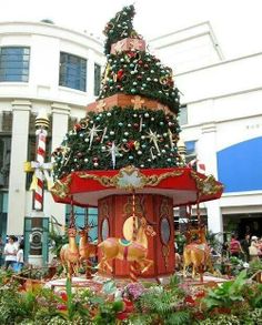 there is a christmas tree on display in the middle of this town square with people walking around it