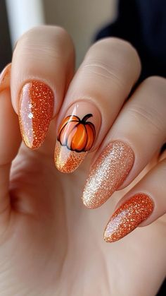 Glitter almond nail for autumn with pumpkin pattern Fall Nail With Pumpkin, Nails Inspiration Pumpkin, Fall Nails With A Pumpkin, Blue Pumpkin Nail Art, Easy Fall Acrylic Nails, Sparkly Pumpkin Nails, Nail Pumpkin Designs