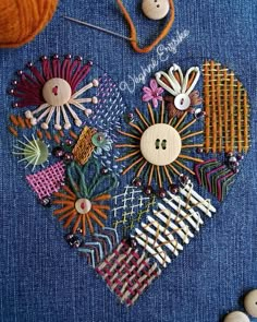 a heart made out of buttons and pins sitting on top of a blue piece of cloth