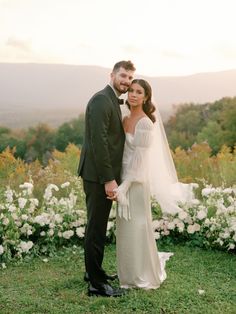 a bride and groom pose for a photo in front of white flowers at their wedding