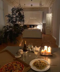 a table with pizza, wine and candles on it