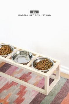 two bowls with food in them sitting on a wooden stand next to a rug and white wall