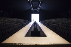 an empty room with rows of chairs and a person standing in the doorway at the end