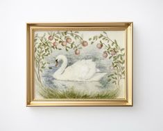 a white swan floating on top of a body of water under a tree filled with fruit