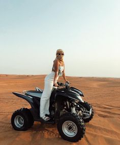 a woman riding on the back of a four - wheeler in the middle of desert