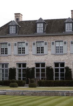 a large brick building with many windows and bushes