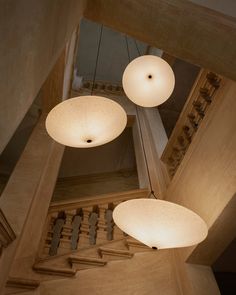 three lights hanging from the ceiling in a room with stairs and railings on both sides