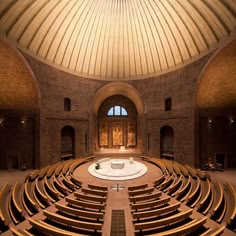 an empty auditorium with wooden seats and a round table in the center is seen from the front