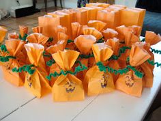 an arrangement of orange paper bags on a table with green ribbon around the edges and decorations