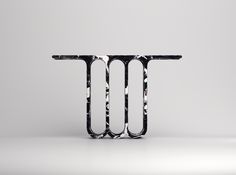 a black and white object with the letter t on it's side, in front of a gray background