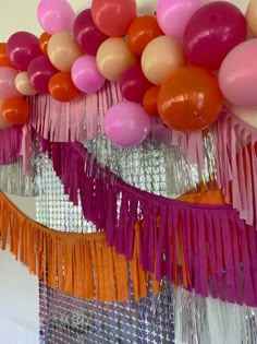 balloons and streamers are hanging from the ceiling in front of a mirror that is decorated with fringes