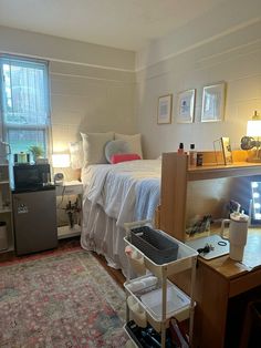 a room with a bed, desk and computer on it in front of a window