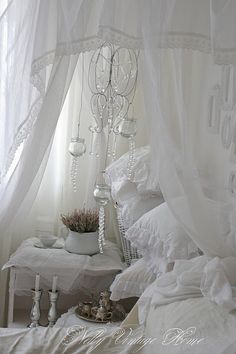 a bedroom with white bedding and chandelier hanging from it's ceiling