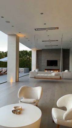 a living room filled with white furniture and a fire place in the middle of it